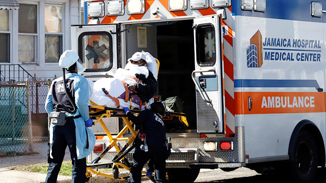Emergency Medical Technicians (EMT) lift a patient into an ambulance 