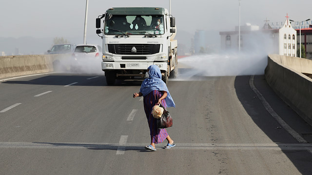 A woman wearing a face mask, runs in front of a truck spraying disinfectant on the street as part of measures to prevent the potential spread of coronavirus (COVID-19), in Addis Ababa, Ethiopia March 29, 2020. REUTERS/Tiksa Negeri

