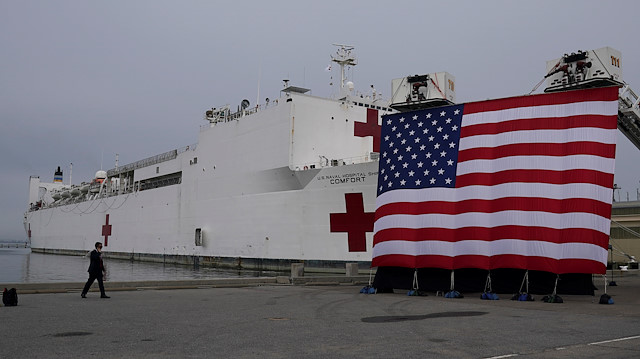 The hospital ship USNS Comfort, which will depart for New York to help with the coronavirus disease (COVID-19) crisis, sits behind a big flag prior to the arrival of U.S. President Donald Trump to give the ship a send-off at Naval Station Norfolk, in Norfolk, Virginia, U.S., March 28, 2020. REUTERS/Kevin Lamarque

