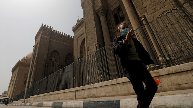 A man wearing a face mask walks past Al-Rifa'i Mosque