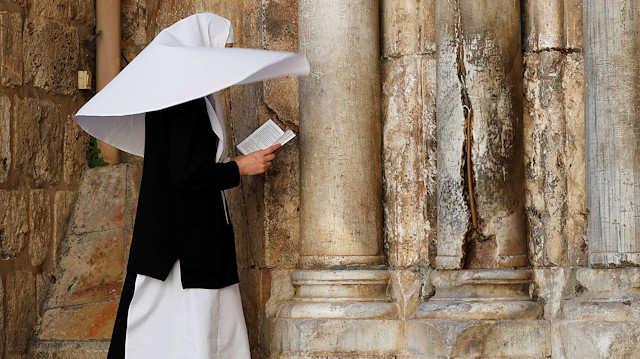 A nun prays in front of the closed front door of the Church of the Holy Sepulchre amid coronavirus restrictions in Jerusalem's Old City March 26, 2020 REUTERS/ Ammar Awad

