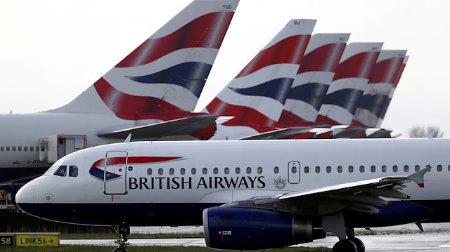 FILE PHOTO: A British Airways plane taxis past tail fins of parked aircraft to the runway near Terminal 5 at Heathrow Airport in London, Britain March 14, 2020
