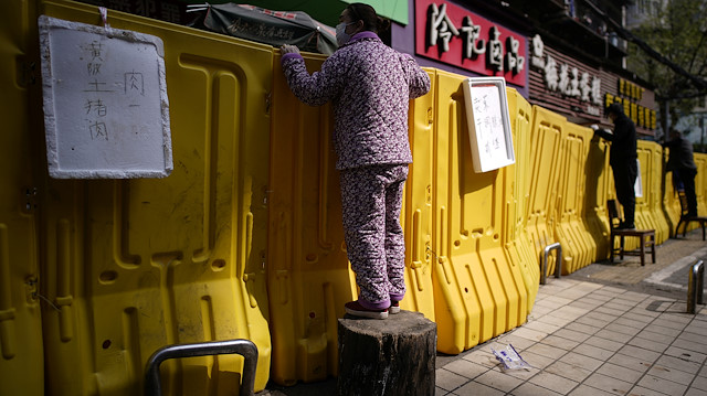 Residents pay for groceries by standing on chairs to peer over barriers set up to ring fence a wet market on a street in Wuhan, Hubei province, the epicentre of China's coronavirus disease (COVID-19) outbreak, April 1, 2020. REUTERS/Aly Song

