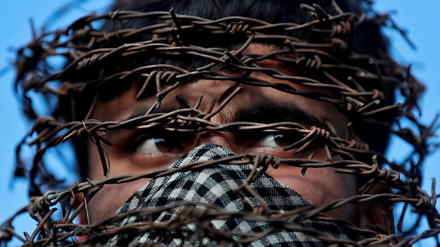 A masked Kashmiri man with his head covered with barbed wire attends a protest after Friday prayers during restrictions following the scrapping of the special constitutional status for Kashmir by the Indian government, in Srinagar, October 11, 2019. REUTERS/Danish Ismail

