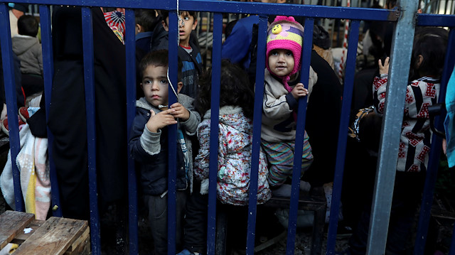 Children stand next to a metal barrier as newly-arrived refugees and migrants wait to be registered at the Moria camp, on the island of Lesbos, Greece, November 27, 2019.