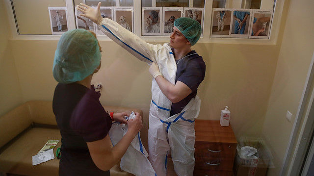 Bir tıp uzmanı, koronavirüs hastasını tedavi etmeden önce koruyucu giysilerini giyiyor.