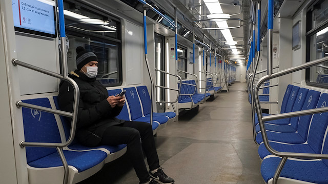 A man wearing a protective mask checks his phone as he rides in a metro train, after the city authorities announced a partial lockdown ordering residents to stay at home to prevent the spread of coronavirus disease (COVID-19), in Moscow, Russia April 3, 2020