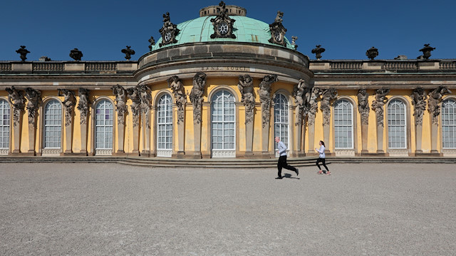 Joggers run past Sans Souci Castle, as the spread of coronavirus disease (COVID-19) continues in Potsdam, Germany, April 5, 2020. REUTERS/Reinhard Krause

