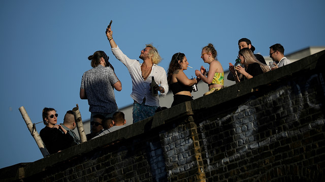 FILE PHOTO: People enjoy warm weather on a rooftop as the spread of the coronavirus disease (COVID-19) continues, in London, Britain, April 5, 2020. To match Special Report HEALTH-CORONAVIRUS/BRITAIN-PATH REUTERS/Marika Kochiashvili/File Photo

