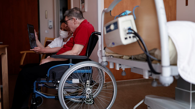 Health worker Emilie Neumann helps a 79 year-old resident to attend an online video call with his relatives at Les Jardins d'Emeraude long-term care unit at Bischwiller departemental hospital, near Strasbourg, during a lockdown imposed to slow the spread of the coronavirus disease (COVID-19), France, April 9, 2020