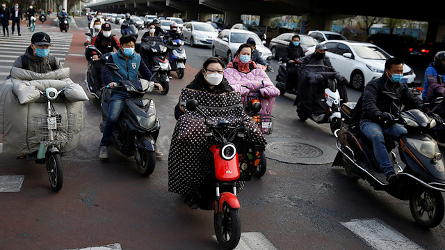 People wearing face masks are seen at Beijing's Financial Street during evening rush hour