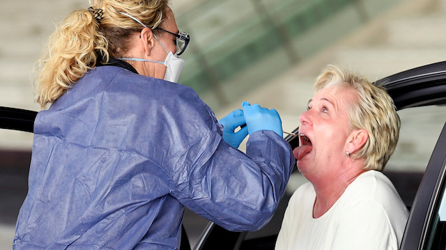 A member of medical staff takes coronavirus test samples of a woman 