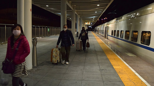 Maske takan yolcular, tren istasyonunda bekliyor.