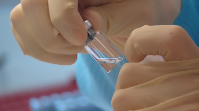 A scientist cleans vaccine vials at the Clinical Biomanufacturing Facility (CBF) in Oxford, Britain