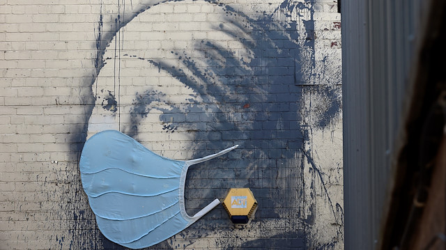 A piece of Banksy street art titled "The Girl with the Pierced Eardrum", now adorned with a protective face mask, is seen at Albion Dock, amid the spread of the coronavirus disease (COVID-19), in Bristol, Britain April 23, 2020. REUTERS/Rebecca Naden 

