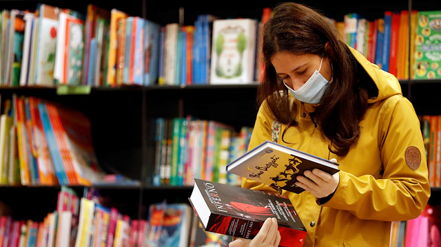 A customer wearing a protective face mask and gloves checks books at a newly opened bookstore, as only very few restrictions are relieved under the coronavirus disease (COVID-19) lockdown rules, in Rome, Italy April 20, 2020. REUTERS/Yara Nardi

