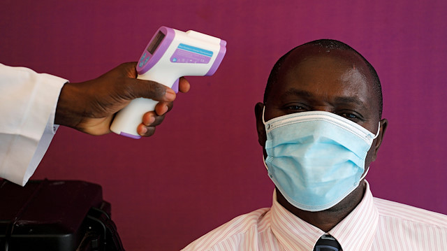 A health worker takes the temperature of a man at a screening 