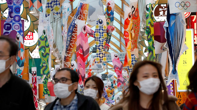 People wearing face masks walk under fluttering Koinobori, traditional Japanese carp-shaped windsocks that are hung in Japan from April to early May to wish a good health for children, following the coronavirus disease (COVID-19) outbreak, in Tokyo, Japan, April 24, 2020. REUTERS/Kim Kyung-Hoon TPX IMAGES OF THE DAY