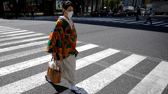 A woman with a face mask wearing a kimono crosses a street in Ginza shopping district 