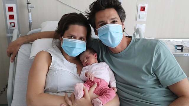 Amandine, who tested positive for the coronavirus disease (COVID-19) just before giving birth, and Francois, wearing protective face masks, are pictured with their newborn daughter Mahaut at the maternity at CHIREC Delta Hospital in Brussels, Belgium April 25, 2020
