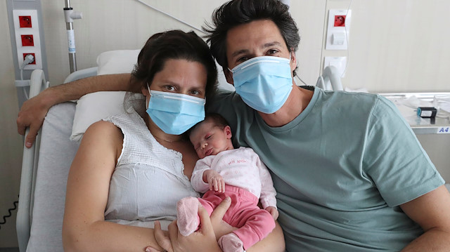 Amandine, who tested positive for the coronavirus disease (COVID-19) just before giving birth, and Francois, wearing protective face masks, are pictured with their newborn daughter Mahaut at the maternity at CHIREC Delta Hospital in Brussels, Belgium April 25, 2020