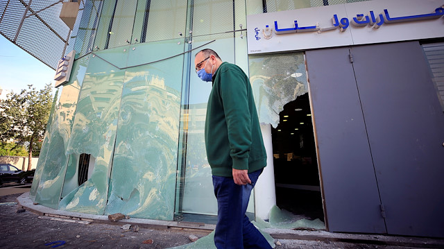 File photo: A man wearing a face mask walks past a damaged facade of a bank, after overnight protests fuelled by worsening economic conditions, in the southern city of Sidon, Lebanon April 30, 2020. 