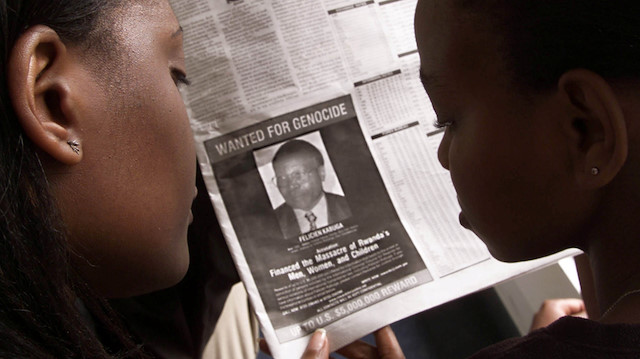 FILE PHOTO: Readers look at a newspaper June 12, 2002 in Nairobi carrying the photograph of Rwandan Felicien Kabuga 