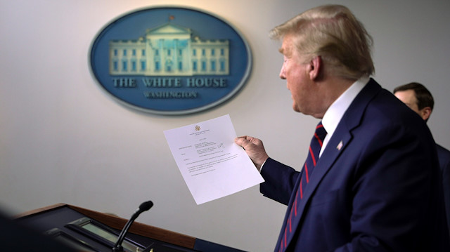 U.S. President Donald Trump holds a letter from White House physician Commander Sean Conley that reports that the president has tested negative a second time for coronavirus disease during a use of the new 15-minute result test at the White House in Washington, U.S., April 2, 2020. REUTERS/Tom Brenner

