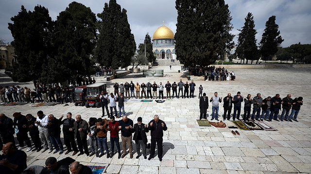 Worshippers pray as the Dome of the Rock is seen in the background 