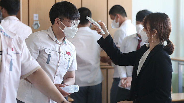 A high school teacher checks body temperature of a student at a classroom following the global outbreak of the coronavirus disease (COVID-19), in Gimhae, South Korea, May 20, 2020. Yonhap/via REUTERS ATTENTION EDITORS - THIS IMAGE HAS BEEN SUPPLIED BY A THIRD PARTY. NO RESALES. NO ARCHIVE. SOUTH KOREA OUT. NO COMMERCIAL OR EDITORIAL SALES IN SOUTH KOREA.

