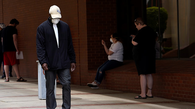 A man who lost his job walks past others as they wait in line to file for unemployment following an outbreak of the coronavirus disease (COVID-19), at an Arkansas Workforce Center in Fort Smith, Arkansas, U.S. April 6, 2020. 