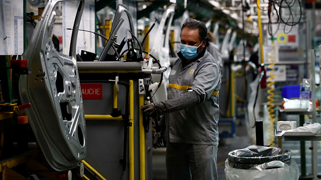 An employee, wearing a protective face mask, works on the automobile assembly line of Renault ZOE cars at the Renault automobile factory in Flins as the French carmaker ramps up car production with new security and health measures during the outbreak of the coronavirus disease (COVID-19) in France, May 6, 2020. 
