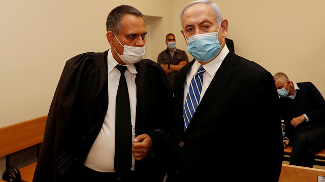 Israeli Prime Minister Benjamin Netanyahu, wearing a mask, stands inside the courtroom as his corruption trial opens at the Jerusalem District Court May 24, 2020. REUTERS/Ronen Zvulun

