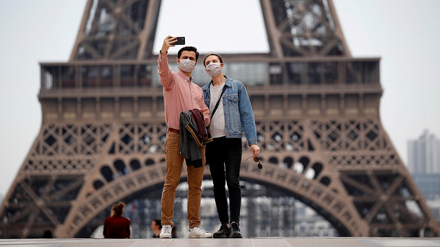FILE PHOTO: People wearing face masks take a selfie at Trocadero square near the Eiffel Tower, as France began a gradual end to a nationwide lockdown due to the coronavirus disease (COVID-19) in Paris, France, May 16, 2020
