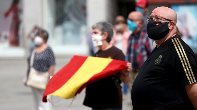 People wearing protective face masks stand during a daily minute of silence to commemorate victims of the coronavirus disease (COVID-19), at Puerta del Sol square in Madrid, Spain, May 26, 2020