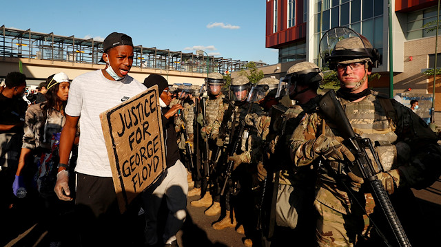 A man holds a sign in the aftermath of a protest against the death in Minneapolis police custody of African-American man George Floyd, in Minneapolis, Minnesota, U.S., May 29, 2020. 