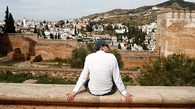 File photo: A tourist sits outside La Alhambra which is closed to visitors due to the coronavirus outbreak, in Granada, Spain March 13, 2020