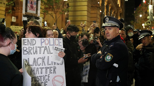 A police officer looks on as people protest in solidarity with those in the United States protesting police brutality and the death in Minneapolis police custody of George Floyd, in Sydney, Australia, June 2, 2020.
