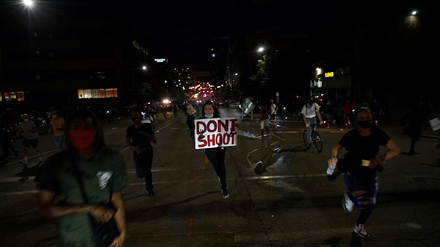File photo: A protestor holding a banner runs away from tear gas during a protest against the death in Minneapolis police custody of African-American man George Floyd, in St Louis, Missouri, U.S., June 1, 2020