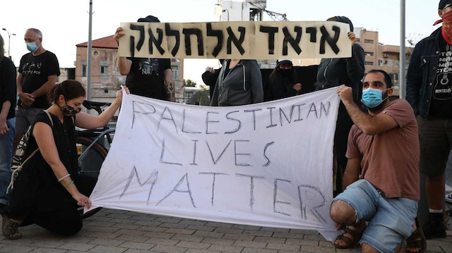 İsrailli aktivistler, ellerinde "Filistinlilerin hayatı önemlidir" sloganı taşıyor.