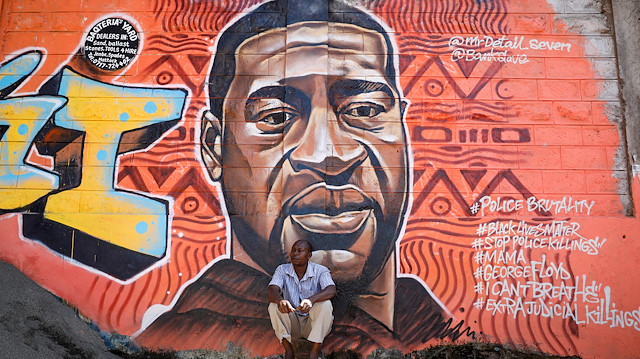 A man sits under a graffiti depicting African-American man George Floyd, who died in Minneapolis police custody, at the Kibera slum of Nairobi, Kenya, June 4,2020.REUTERS/Baz Ratner


