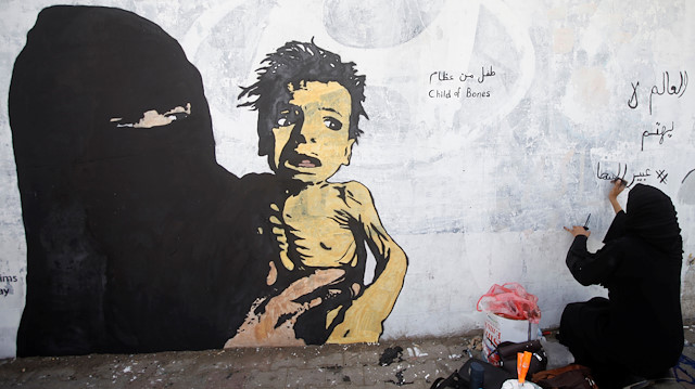 A friend of artist Haifa Subay writes on a mural about children and women suffering in the time of war in Sanaa, Yemen February 21, 2019. Picture taken February 21, 2019. REUTERS/Mohamed al-Sayaghi

