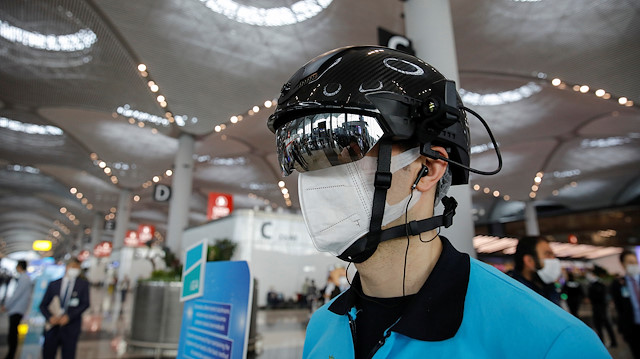An employee wearing a thermal imaging VF helmet monitors passengers at the entrance of Istanbul Airport during the first day of resumed domestic flights which are halted since March 26 amid the spread of the coronavirus disease (COVID-19), in Istanbul, Turkey June 1, 2020. REUTERS/Umit Bektas

