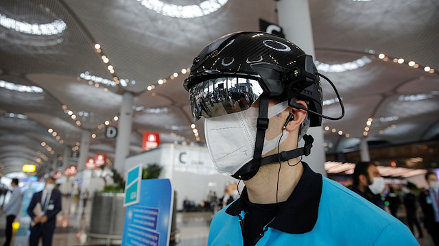 An employee wearing a thermal imaging VF helmet monitors passengers at the entrance of Istanbul Airport during the first day of resumed domestic flights which are halted since March 26 amid the spread of the coronavirus disease (COVID-19), in Istanbul, Turkey June 1, 2020. REUTERS/Umit Bektas