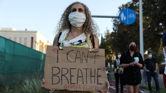 A demonstrator wearing a face mask holds a placard during a protest
