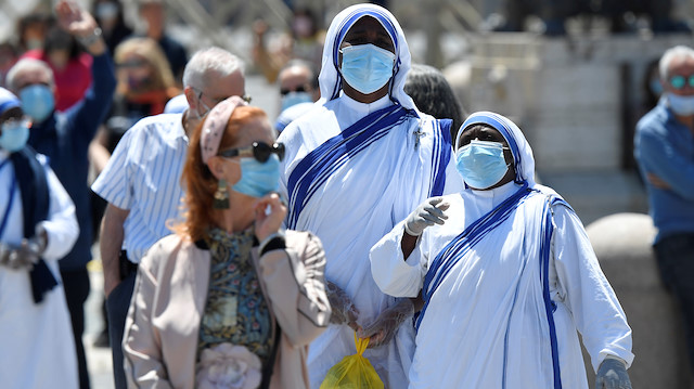 Faithful wear face masks and gloves while Pope Francis leads the Regina Coeli prayer from his window in the newly reopened St. Peter's Square after months of closure due to an outbreak of the coronavirus disease (COVID-19), at the Vatican, May 31, 2020. Vatican Media/­Handout via REUTERS