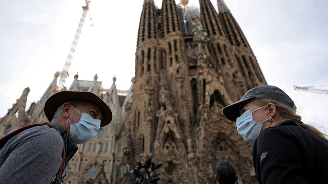 Tourists wear protective face masks as they talk in front of landmark Sagrada Familia basilica, which will stop receiving visitors and suspend its construction work starting from Friday as a precautionary measure due to the coronavirus outbreak in Barcelona