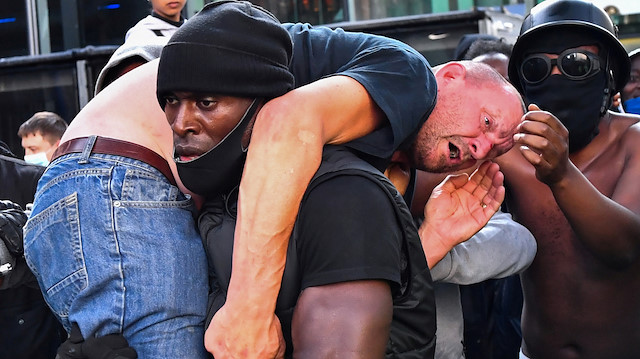 A protester carries an injured counter-protester to safety, near the Waterloo station during a Black Lives Matter protest following the death of George Floyd in Minneapolis police custody, in London, Britain, June 13, 2020. REUTERS/Dylan Martinez

