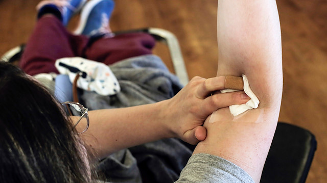 A donor holds her arm after giving blood