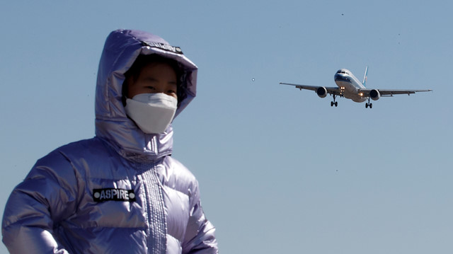 FILE PHOTO: A child wearing a protective mask has her picture taken as a plane of China Southern Airlines lands at Beijing Capital International in Beijing as the country is hit by an outbreak of the novel coronavirus, China, March 13, 2020.